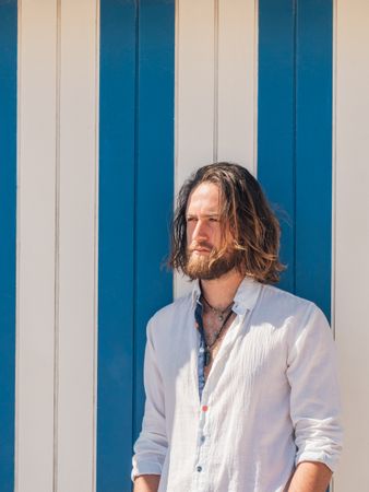 Cheerful guy standing near striped wall
