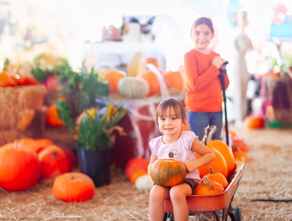 Two Sisters Enjoying a Wagon Ride at a Pumpkin Patch on a Fall Day.