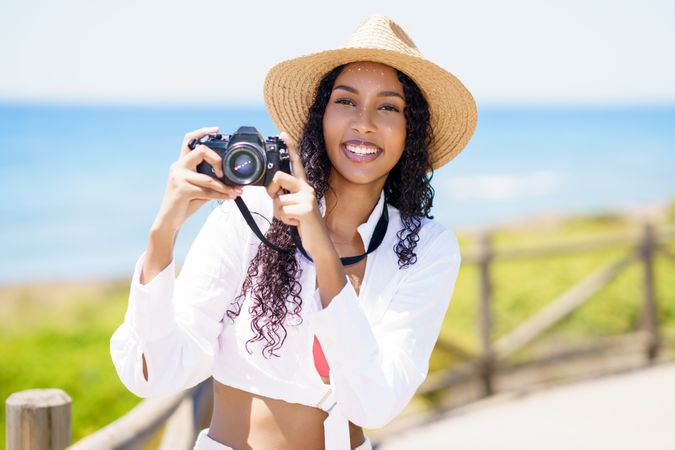 A Joyful Woman Taking Pictures with Her Camera on the Beautiful Beach on a Sunny Day