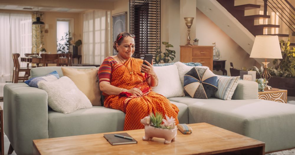 Older Hindu Woman Using Smartphone at Home: Talking with Loved Ones through Video Calls.