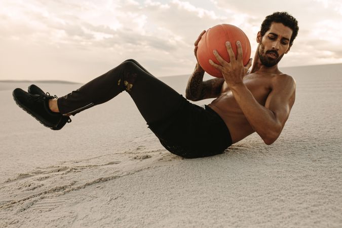 Athlete using a medicine ball for fitness training at desert