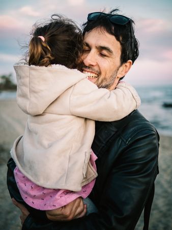 father holding little daughter at the beach