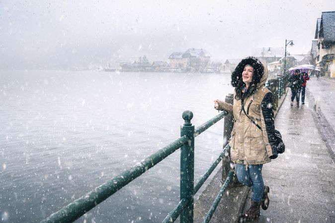 Woman on lakeshore smiling while standing outside in the snow by a lake