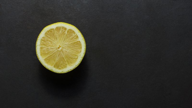 Top view of a half cut lemon placed on a dark background