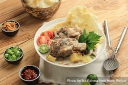 Soto betawi, bowl of Indonesian beef stew served with condiments 0Plr70