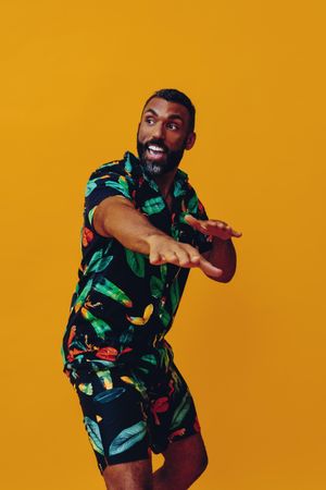 Excited male dancing in brightly patterned shirt and shorts