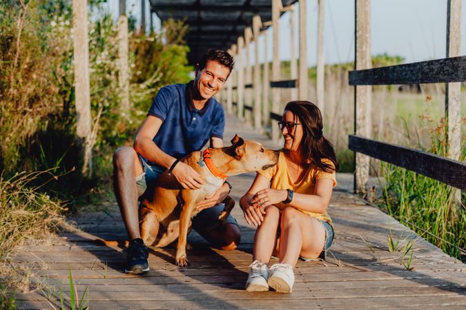 Happy adult couple having fun with dog at countryside