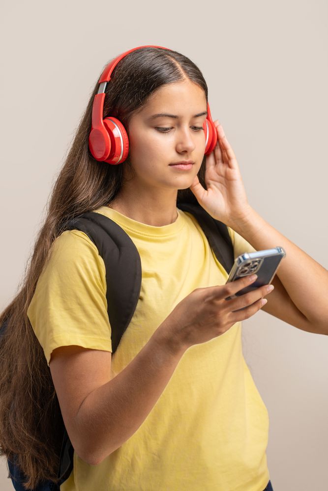 Young student listening to music on headphones while using her smartphone.