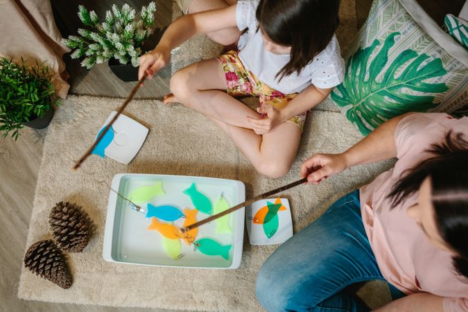 Unrecognizable mother and daughter camping at home playing diy fishing game
