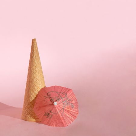 Cone of ice cream with pink cocktail parasol