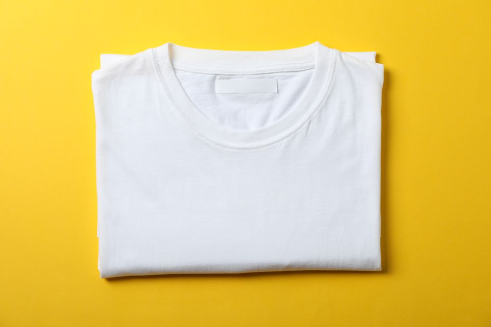 Folded blank plain t-shirt on yellow background, space for text