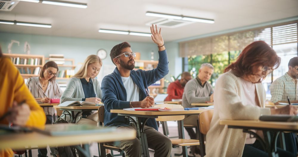 Young Indian Man Raising Hand and Asking Teacher a Question During a Lecture in Adult Education Course in School