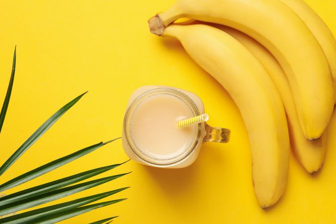Bananas and juice on yellow background. Fresh fruit