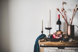 Rustic setting of wine, cheese, long candles, with pomegranate, and dried poppies, with copy space
