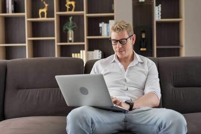 Man working with laptop or watching movie on couch in the living room at home