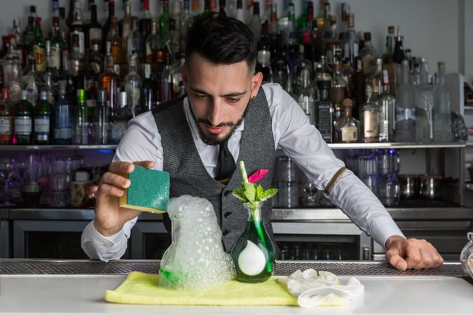 Bartender preparing an alcoholic beverage with foam in clear glass