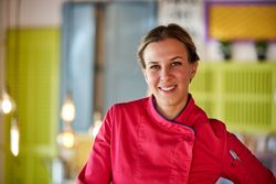Smiling female cook in uniform in colorful room