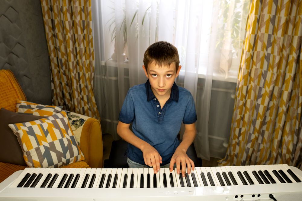 Boy looking up while playing digital piano