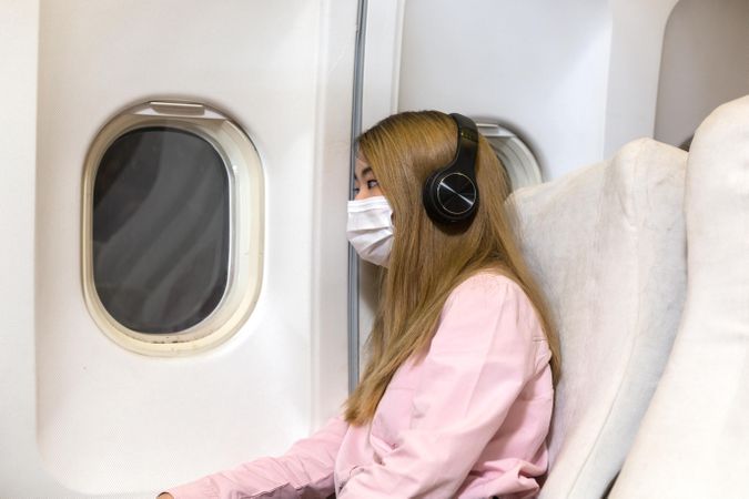 Female passenger in airplane leaning on cabin wall