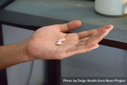 Hand of person with two pills in palm 4d81xn