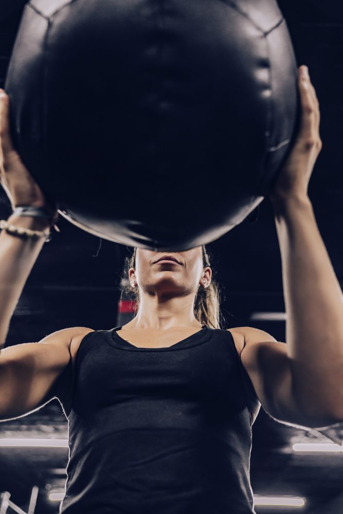 Muscular woman exercising with ball in gym