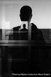 Silhouette of man taking picture in window with reflection 5wEKAb