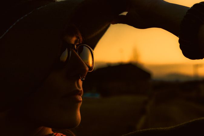 Woman in sunglasses and hat in dark sunset