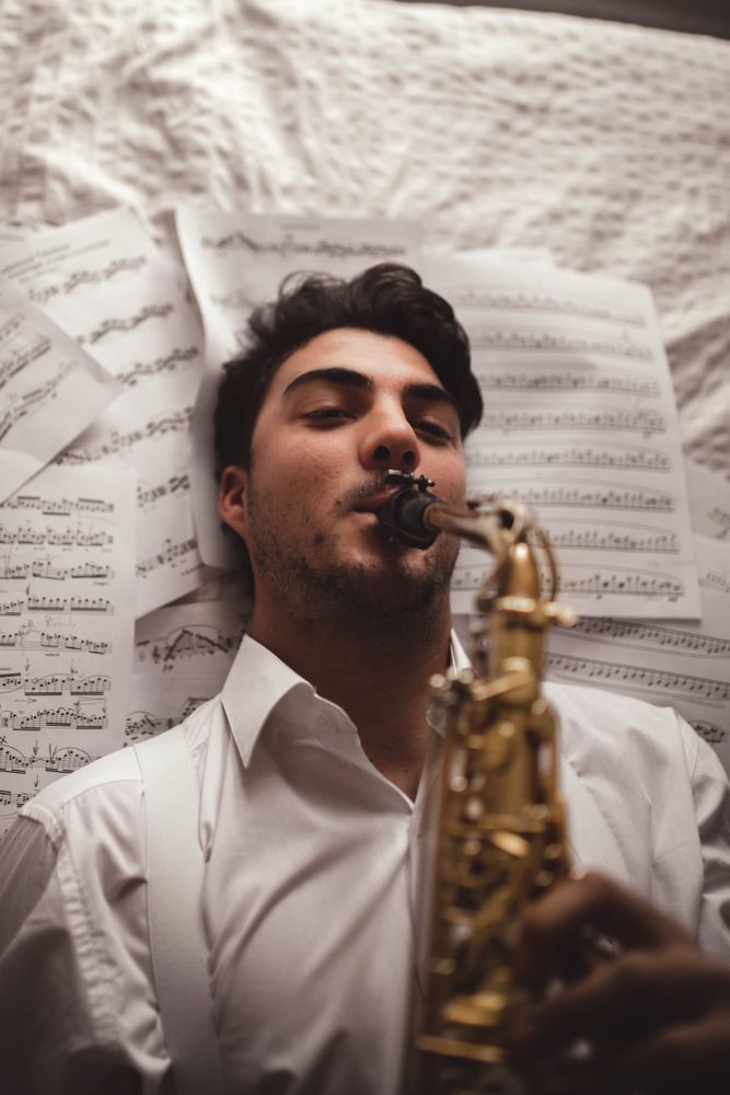 Man playing on saxophone and lying on printed music