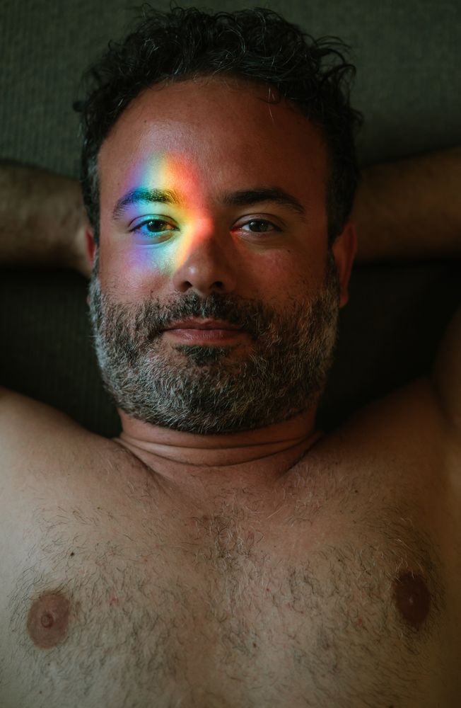 Bearded man with rainbow glare on face