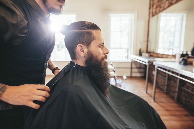 Side view shot of barber with male customer in chair