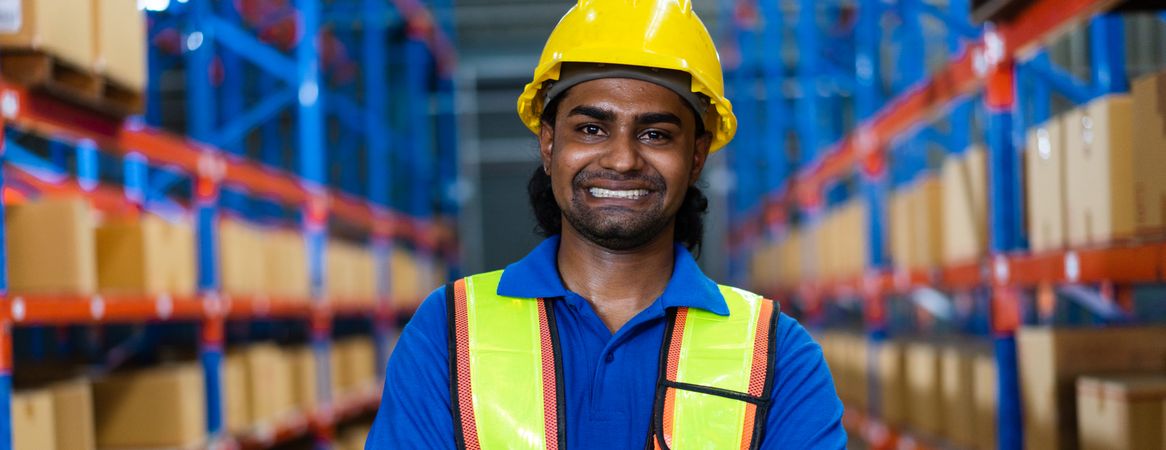 Smiling Indian warehouse worker with vision in safety gear.