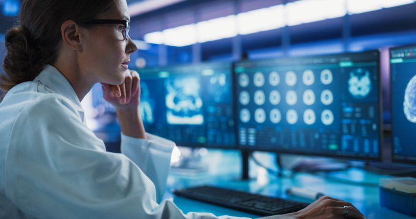 Hospital Research Laboratory: Female Medical Scientist Using Computer with Brain Scan MRI Images.