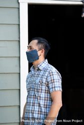Portrait of man standing outside wearing COVID mask smiling and looking away bxABZ0