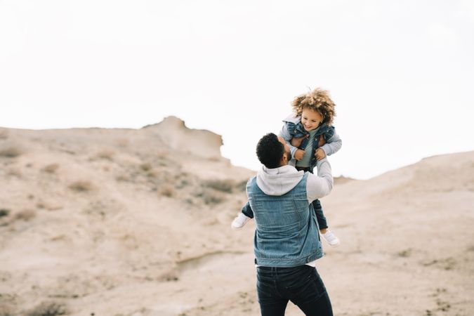 Black father playing with child on ground