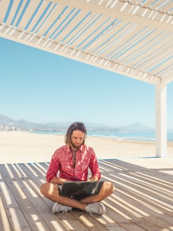 Man using laptop on beach