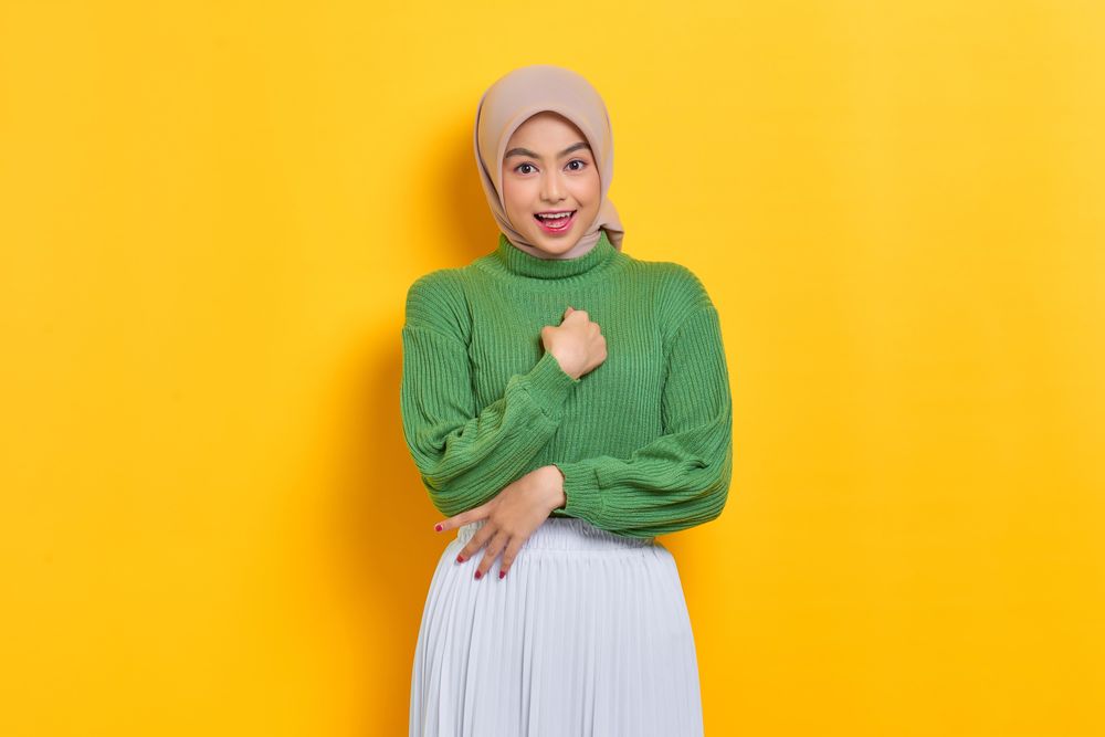 Excited woman in headscarf gesturing at herself