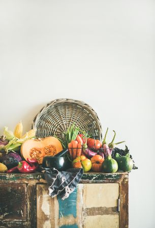 Fresh autumnal produce on counter, with halved squash, and thatched basket with copy space