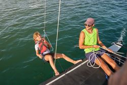 Smiling guy pulling rope with happy kid to make counterweight on