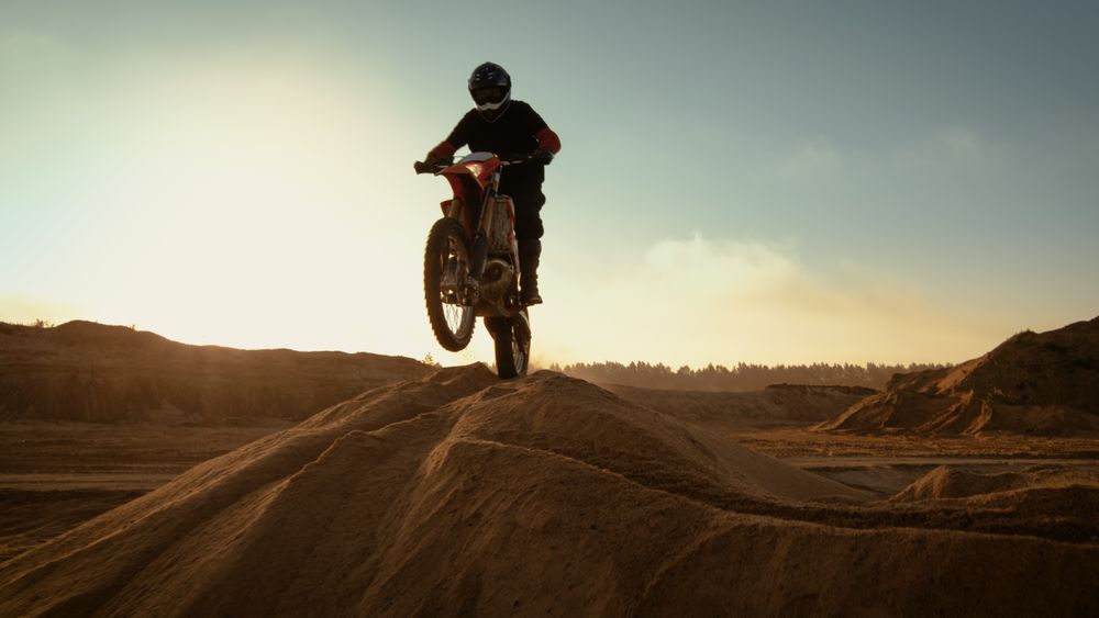 Professional Motocross Motorcycle Rider Driving Over the Dune and Further Down the Off-Road Track.