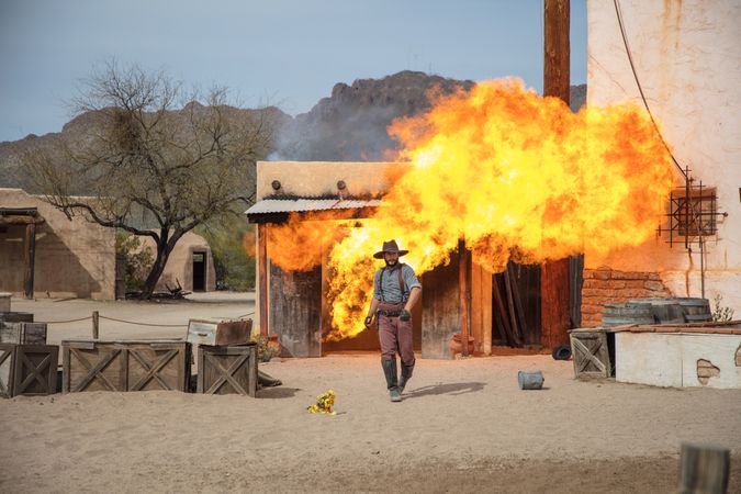 Cowboy walking away from fiery explosion on movie set