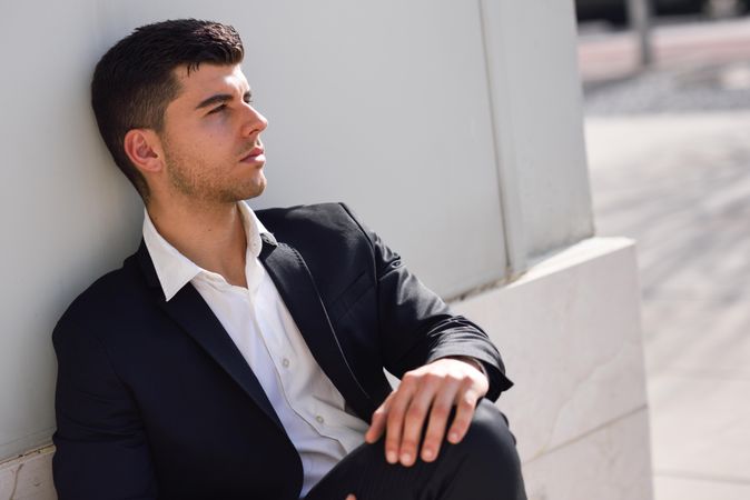 Man in suit leaning on wall outside