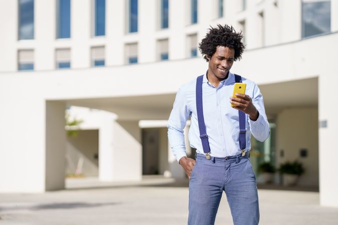 Smiling man looking at phone screen outside in the sunshine