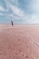 Happy relaxed travelers enjoying unusual scenery of pink salt lake in sunny day
