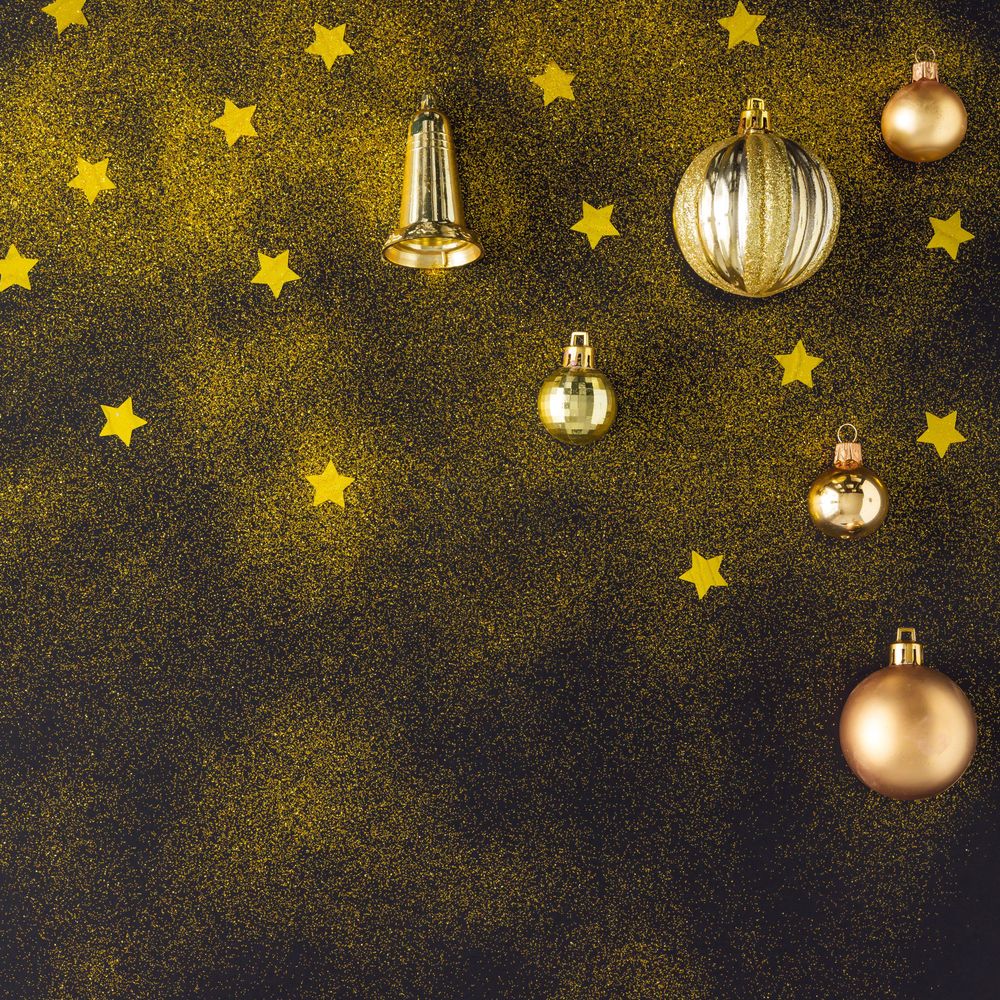 Golden Christmas decorations of stars, glitter bells and baubles on dark background