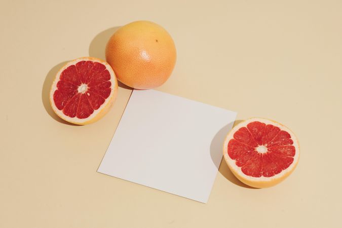 Grapefruit halved with paper card on beige background