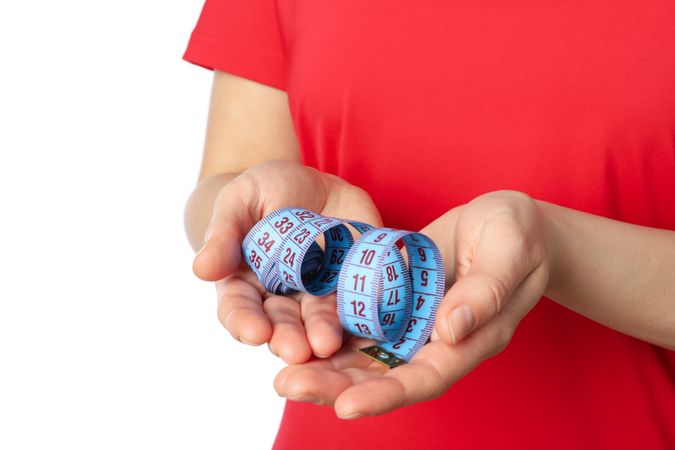 Woman holds measuring tape, isolated on blank background. Healthy lifestyle