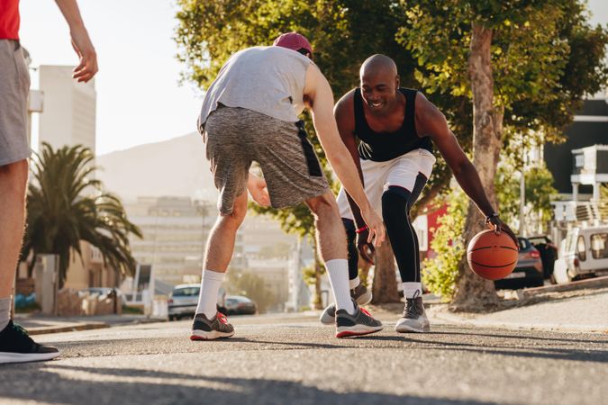 Men practicing basketball dribbling skills on street