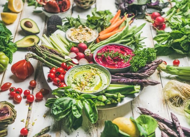 Fresh colorful vegetables and dips with hummus, avocados, asparagus, carrots, horizontal composition