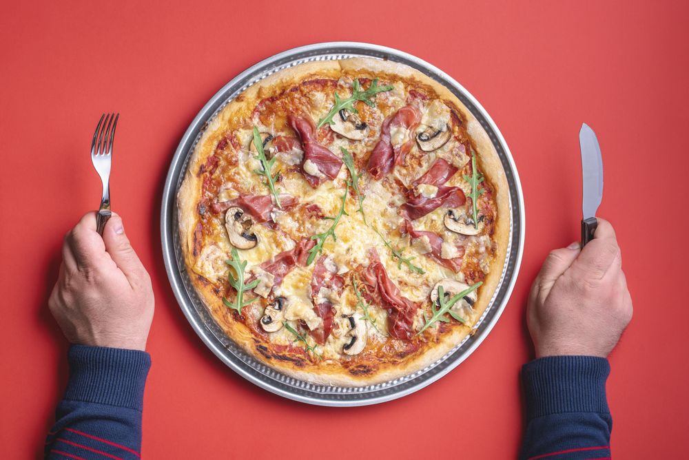 Man hands holding knife and fork ready to eat pizza