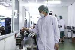 Male on production line of bottling plant in facemask and hairnet